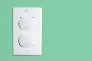 Isolated wall socket on green wall with secturity caps